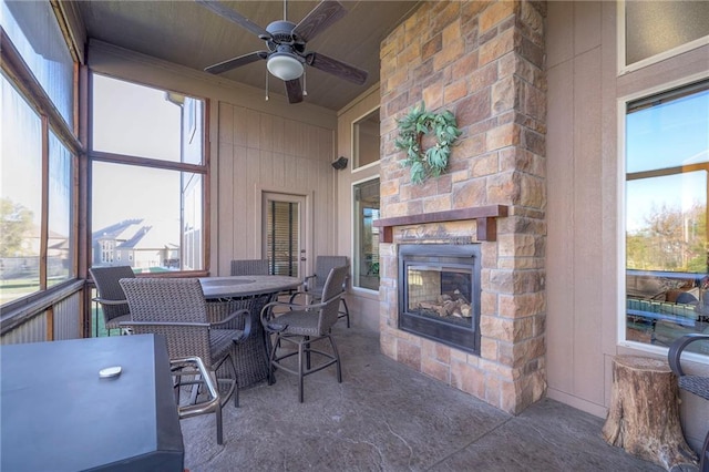 sunroom / solarium with an outdoor stone fireplace and ceiling fan