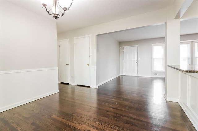 unfurnished room with dark hardwood / wood-style flooring and an inviting chandelier