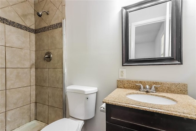 bathroom featuring tiled shower, vanity, and toilet