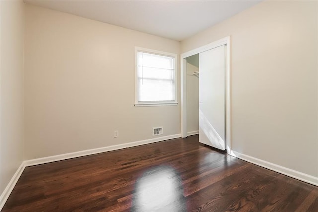 unfurnished bedroom with a closet and dark hardwood / wood-style floors