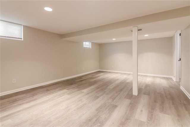 basement with a wealth of natural light and light hardwood / wood-style flooring