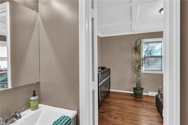 kitchen with dark hardwood / wood-style flooring, crown molding, coffered ceiling, and sink