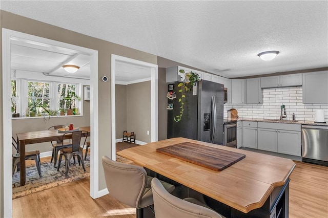 kitchen with appliances with stainless steel finishes, light hardwood / wood-style floors, gray cabinets, and sink