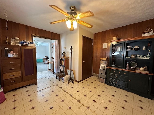 interior space featuring ceiling fan and wood walls