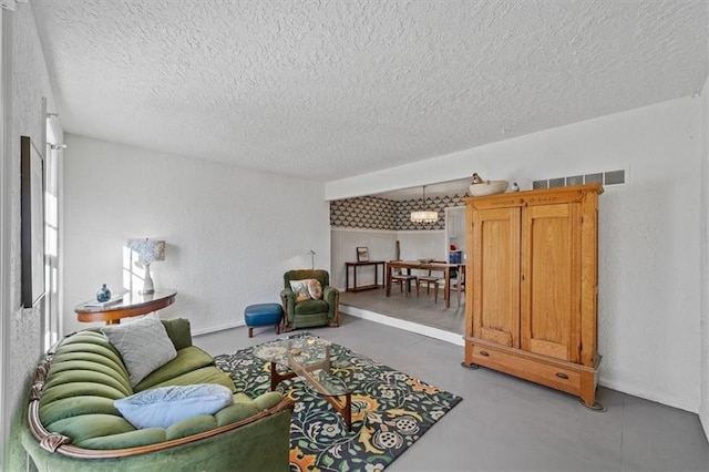 living area with concrete flooring, visible vents, a textured wall, and a textured ceiling