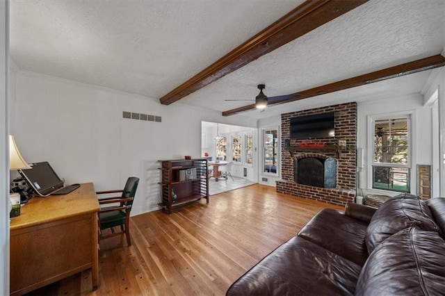 living area with beamed ceiling, wood finished floors, visible vents, and a healthy amount of sunlight