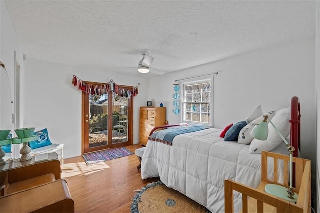 bedroom featuring a textured ceiling, access to outside, wood finished floors, and a ceiling fan