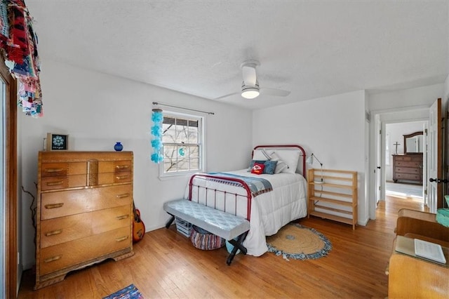 bedroom with a textured ceiling, wood finished floors, and a ceiling fan