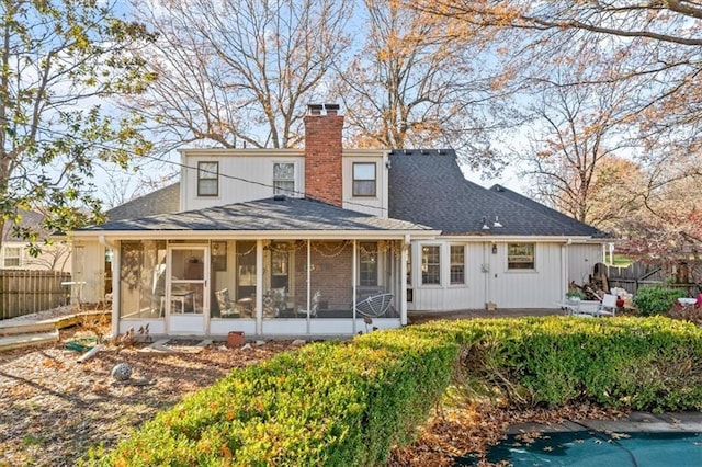 back of property with roof with shingles, a chimney, fence, and a sunroom