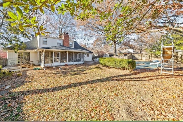 rear view of house with a chimney, fence, and a sunroom