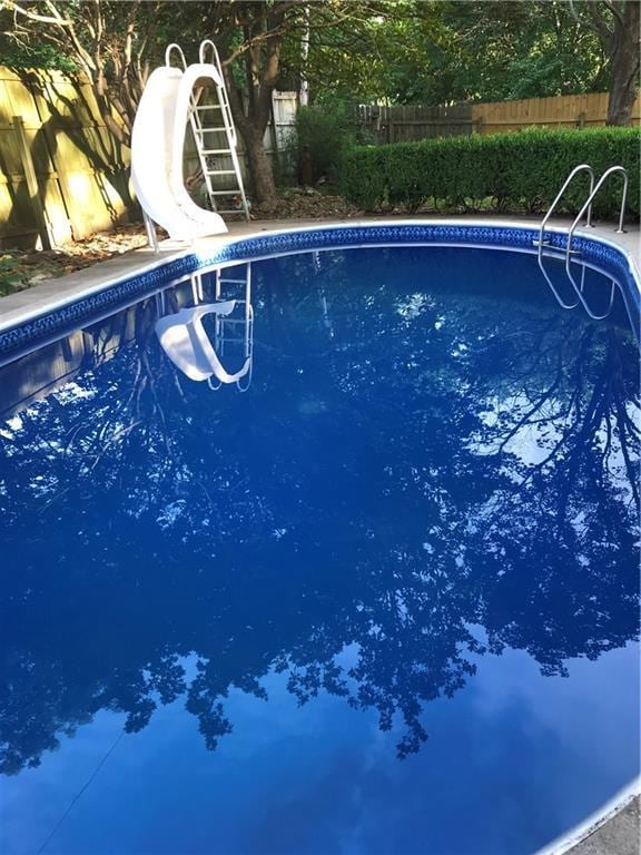 view of swimming pool featuring a fenced in pool, a water slide, and fence