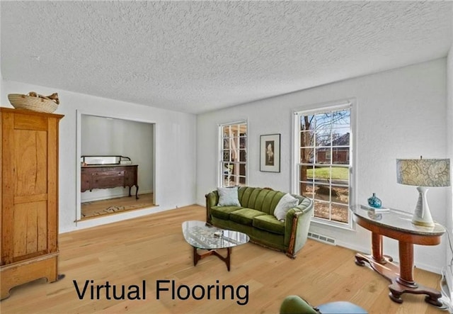 living area with visible vents, a textured ceiling, and wood finished floors