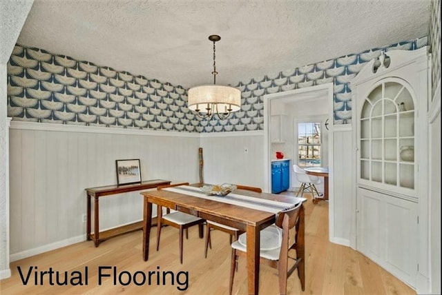 dining area featuring a textured ceiling, wallpapered walls, light wood finished floors, and baseboards