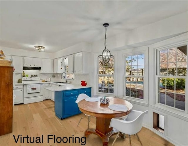 kitchen featuring white electric stove, light countertops, a sink, blue cabinets, and under cabinet range hood