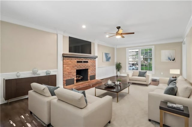 living room with hardwood / wood-style flooring, ceiling fan, ornamental molding, and a brick fireplace