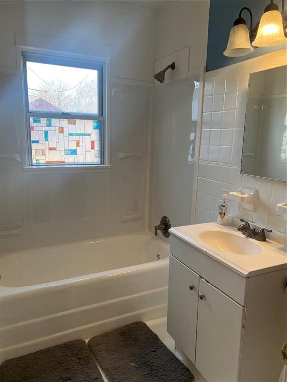 bathroom with vanity, washtub / shower combination, and backsplash