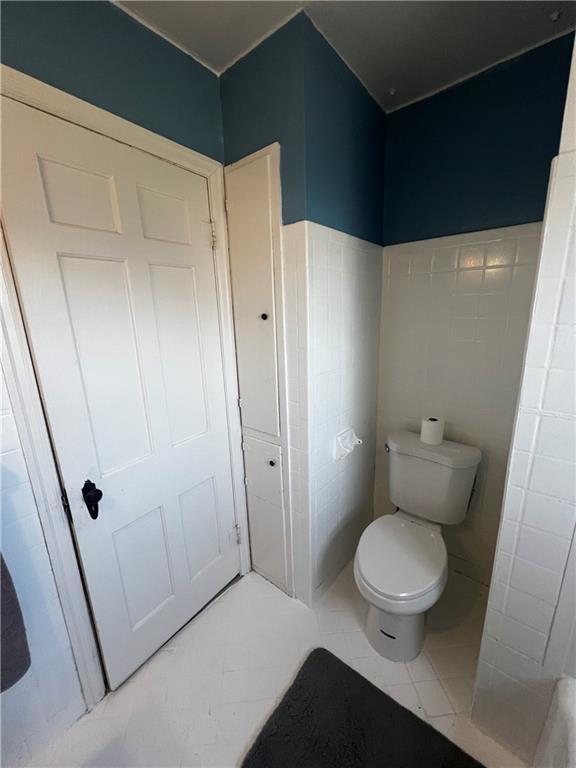 bathroom with tile patterned floors, tile walls, and toilet