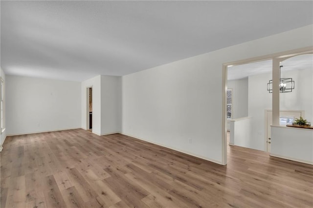 spare room featuring a chandelier and light hardwood / wood-style floors