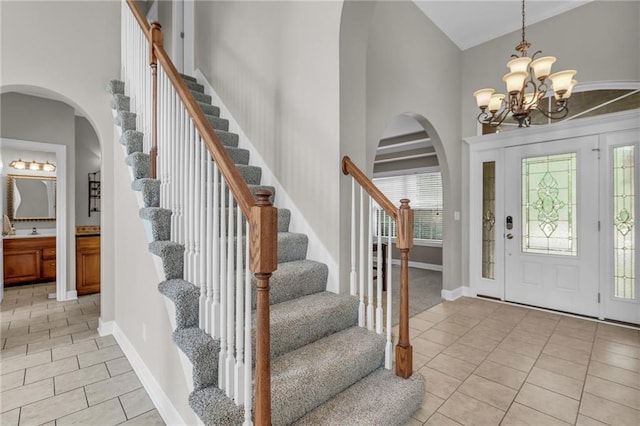 entrance foyer with a notable chandelier, light tile patterned flooring, and a towering ceiling