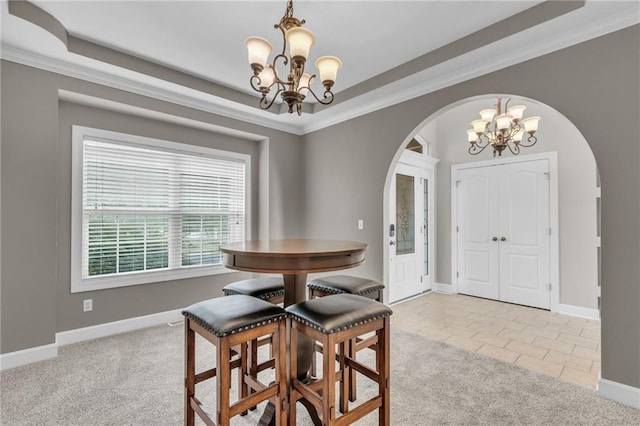 carpeted dining area featuring a raised ceiling, ornamental molding, and an inviting chandelier