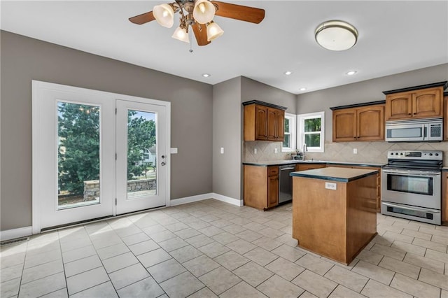 kitchen featuring backsplash, stainless steel appliances, ceiling fan, sink, and a center island