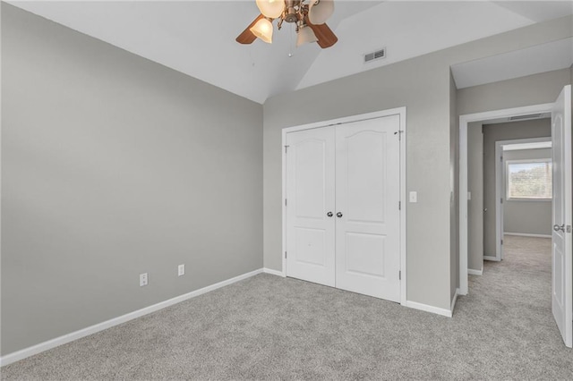 unfurnished bedroom with ceiling fan, a closet, light carpet, and vaulted ceiling