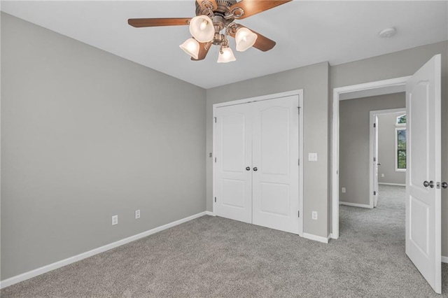 unfurnished bedroom featuring ceiling fan, a closet, and light colored carpet