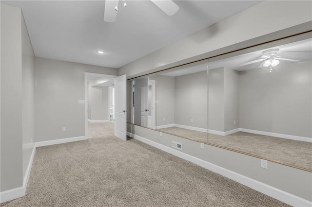 basement featuring light carpet and ceiling fan