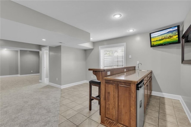 kitchen featuring sink, stainless steel dishwasher, kitchen peninsula, a breakfast bar, and light tile patterned flooring