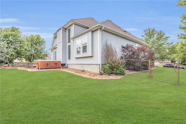 view of side of home featuring a yard and a hot tub