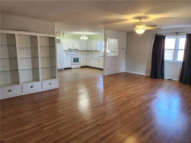 unfurnished living room with dark wood-type flooring, sink, ceiling fan with notable chandelier, and a textured ceiling