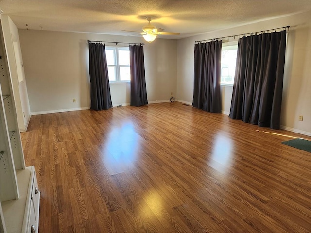 unfurnished room featuring wood-type flooring, a wealth of natural light, a textured ceiling, and ceiling fan