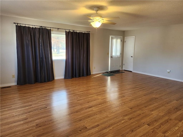 empty room featuring wood-type flooring, ceiling fan, and a textured ceiling