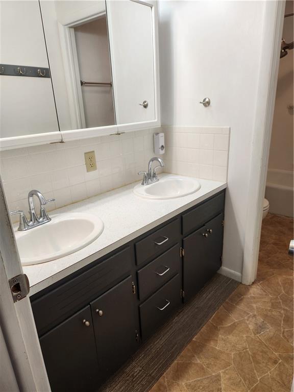 bathroom featuring tasteful backsplash, vanity, a bathing tub, and toilet