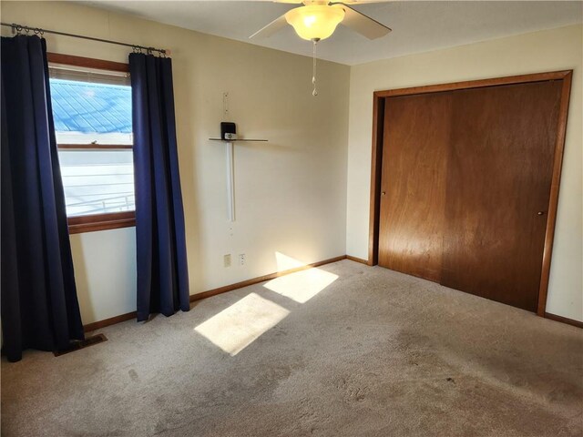 unfurnished bedroom featuring light carpet, ceiling fan, and a closet