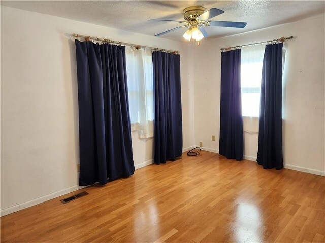 unfurnished room featuring ceiling fan, light hardwood / wood-style flooring, and a textured ceiling