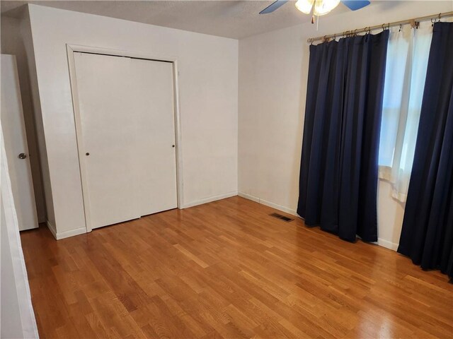 unfurnished bedroom featuring light hardwood / wood-style flooring, a closet, and ceiling fan