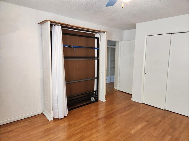 unfurnished bedroom featuring ceiling fan, a closet, a textured ceiling, and light hardwood / wood-style flooring