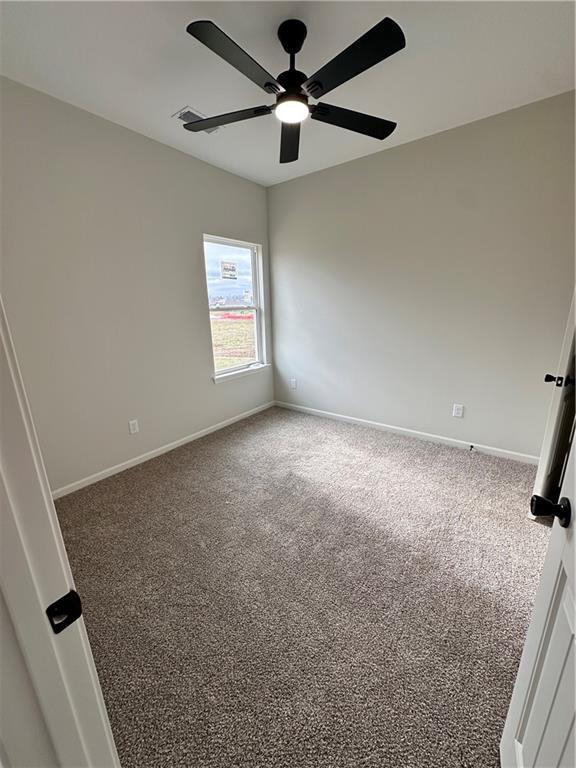 carpeted spare room featuring ceiling fan