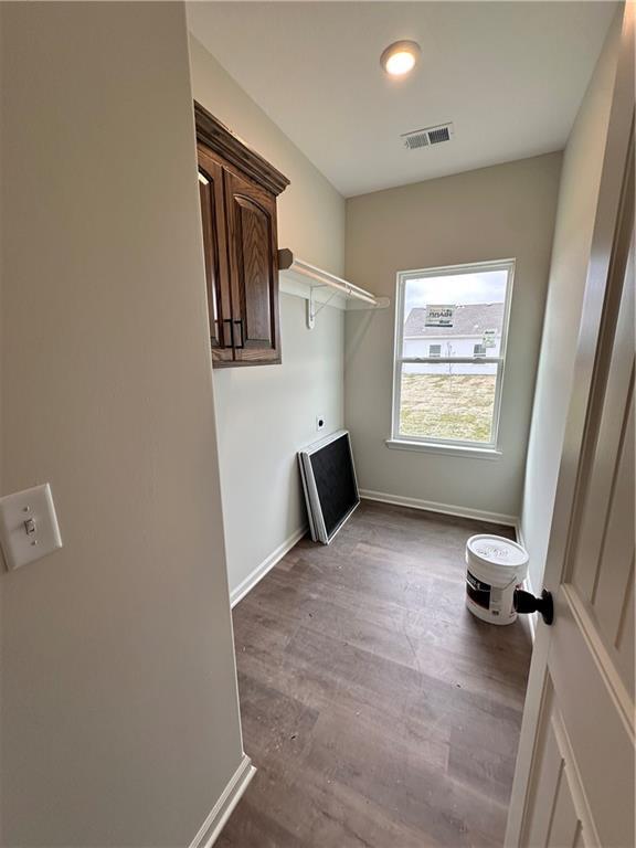 laundry area featuring cabinets, wood-type flooring, and hookup for an electric dryer