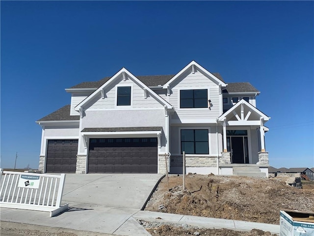 view of front facade featuring a garage, stone siding, roof with shingles, and concrete driveway