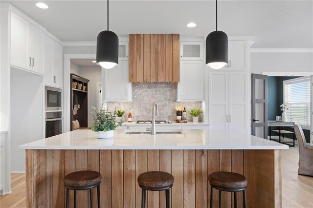 1516 NW 106th St, Kansas City, MO 64155 - kitchen with stainless steel oven, backsplash, ornamental molding, and light wood-style floors