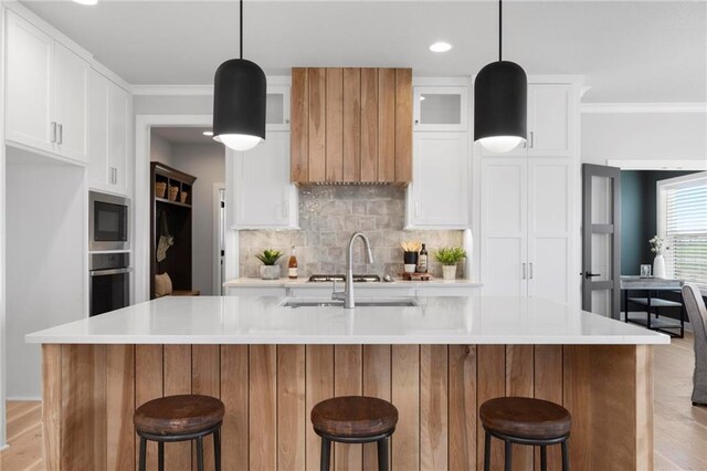 1516 NW 106th St, Kansas City, MO 64155 - kitchen with light wood-style flooring, a sink, decorative backsplash, light countertops, and appliances with stainless steel finishes