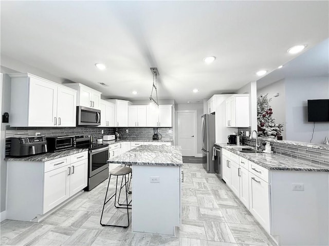 kitchen featuring a center island, sink, a breakfast bar, white cabinets, and appliances with stainless steel finishes