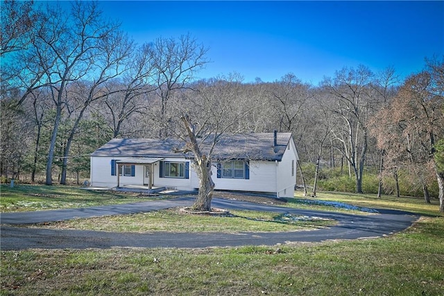 view of front of house with a forest view, a front lawn, and aphalt driveway