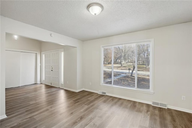 empty room with wood-type flooring and a textured ceiling