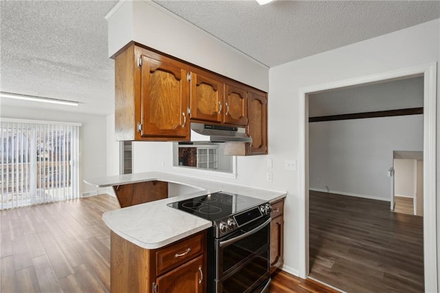 kitchen featuring kitchen peninsula, a textured ceiling, electric range, and dark hardwood / wood-style floors