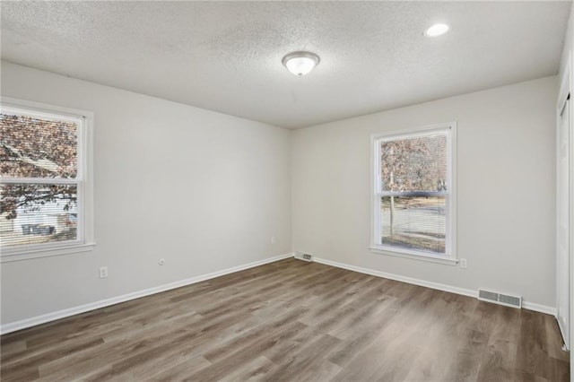 empty room featuring a textured ceiling and dark hardwood / wood-style floors