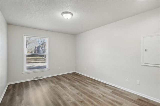 spare room featuring hardwood / wood-style floors and a textured ceiling