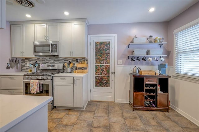 kitchen with tasteful backsplash, white cabinetry, and appliances with stainless steel finishes